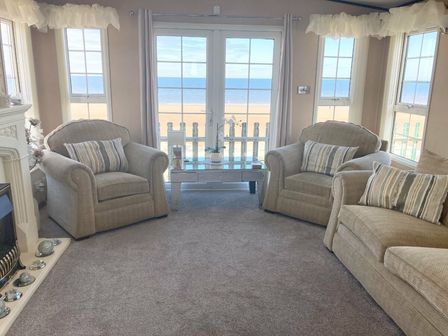 a living room with two armchairs and a view of the beach at Golden Sands Kinmel Bay - Holiday Accommodation 11491 in Kinmel Bay