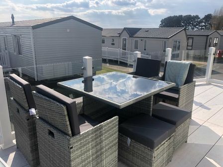a dining set with a glass table and chairs on a patio at Rockley Park - Holiday Accommodation 11506 Poole