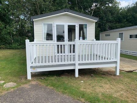 a holiday home with a white deck and railing at Cherry Tree Holiday Park - Holiday Accommodation 11677 Near Great Yarmouth