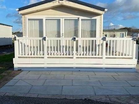 a holiday home with a white deck and large windows at Lido Beach Holiday Park - Holiday Accommodation 11728, Prestatyn