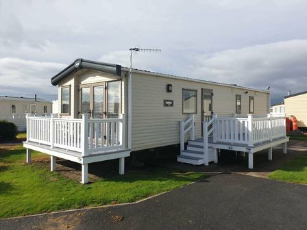 a static caravan with a white deck and steps at Greenacres Holiday Park - Holiday Accommodation 11795 in Porthmadog