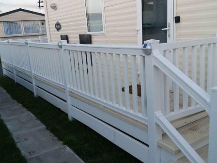 a white railing and steps leading up to an entrance at Lyons Robin Hood - Holiday Accommodation 11874 Prestatyn