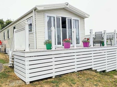a holiday home with a deck and pink and green flower pots at Swanage Bay View - Holiday Accommodation 11907, Swanage