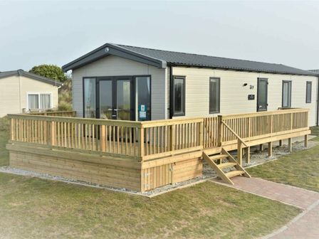 a holiday cabin with a wooden deck and steps at Perran Sands - Holiday Accommodation 12174 in Perranporth