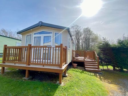 a holiday home with wooden decking and steps set in a grassy area at Hafan y Mor Haven - Holiday Accommodation 12264, Pwllheli