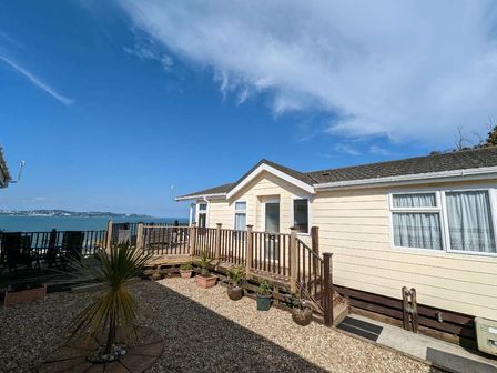a beachfront property with wooden decking and a palm tree at Waterside, Paignton - Holiday Accommodation 12473, Paignton