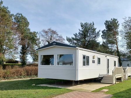 a side view of a white mobile home with steps at Hafan y Mor Haven - Holiday Accommodation 12637 Pwllheli