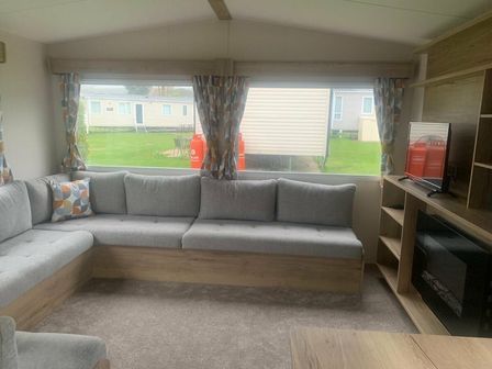 a living room with a gray sectional sofa and a television at Weymouth Bay Holiday Park - Holiday Accommodation 12761, Weymouth