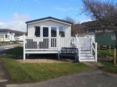a holiday home with a deck and bench at Challaborough Bay Holiday Park - Holiday Accommodation 12878 in Kingsbridge