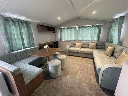 a living room with a sectional sofa, a dining table, and green curtains at Butlins Minehead - Holiday Accommodation 13288 in Minehead