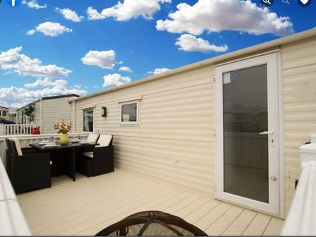a patio area with a table and chairs alongside a door at Cayton Bay Caravan Park - Holiday Accommodation 13460, Cayton