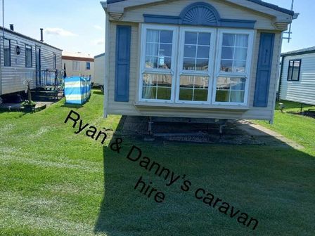 a caravan with a blue and white exterior in a grass area at Edwards Leisure Park - Holiday Accommodation 13496 Towyn