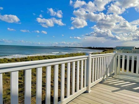 a view of the sea from a deck with white railings at Sandy Bay Holiday Park - Holiday Accommodation 13556 Newbiggin By The Sea