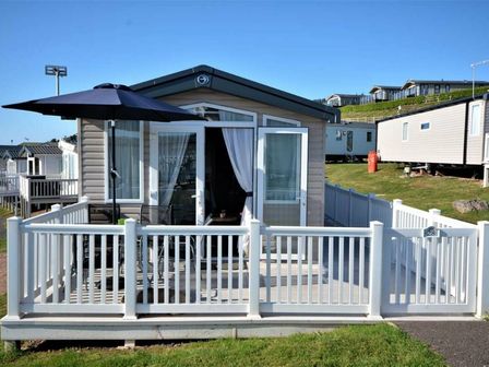 a holiday home with a patio area and umbrella at Devon Cliffs Holiday Park - Holiday Accommodation 13632, Exmouth