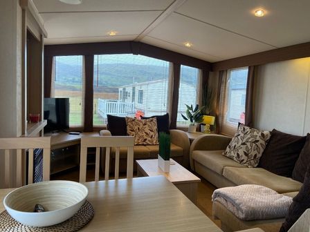 a living room with a sofa and armchairs at Lyons Sunnysands Holiday Park - Holiday Accommodation 13960 Barmouth