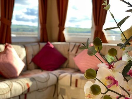 a corner seating area with cushions and a flower arrangement at Cambrian Coast Holiday Park - Holiday Accommodation 14157 in Borth