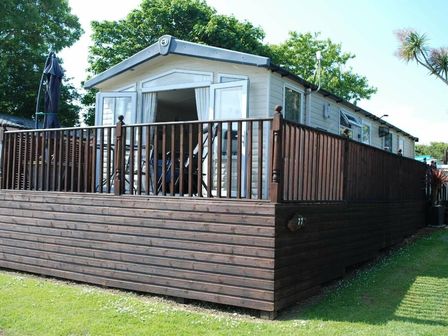a holiday home with a wooden deck and railing at Trevella Park - Holiday Accommodation 14424, Newquay