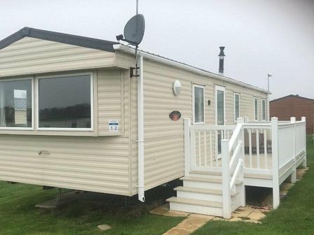 a caravan with a porch and lawn area at Cayton Bay Caravan Park - Holiday Accommodation 14501 Scarborough