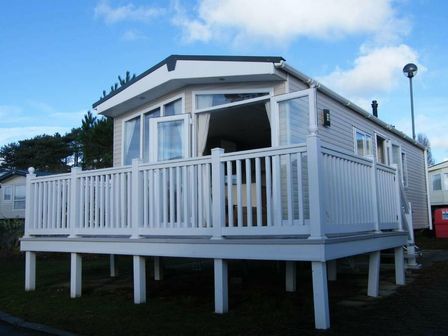 a holiday home with a white deck and large windows at Rockley Park - Holiday Accommodation 14574 in Poole