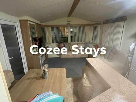a spacious sitting area with large windows and seating at Cozee Stays in Rhyl