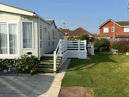 a mobile home with stairs and a garden area at Lido Beach Holiday Park - Holiday Accommodation 14905 Prestatyn