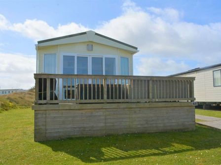 a holiday home with a deck on a grassy area at Perran Sands - Holiday Accommodation 15012 Perranporth
