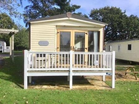a holiday home with a deck and patio area at Hopton Holiday Village - Holiday Accommodation 15319 in Great Yarmouth