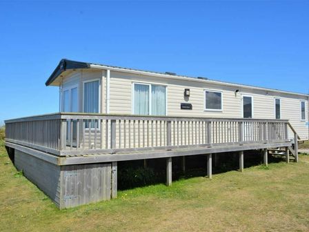 a holiday home on stilts with a wooden deck at Perran Sands - Holiday Accommodation 15598 Perranporth