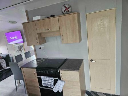 a kitchen with a stove and cabinet next to a door at Ty Mawr Holiday Park - Holiday Accommodation 15822, Abergele