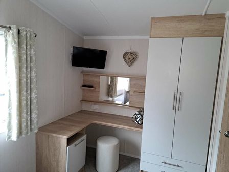 a bedroom with a dressing area, a TV mounted on the wall, and a storage unit at Hafan y Mor Haven - Holiday Accommodation 16015 Pwllheli