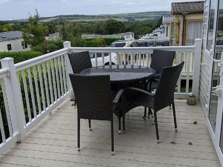 a patio area with a round table and four chairs at White Acres Holiday Park - Holiday Accommodation 16206 in Newquay