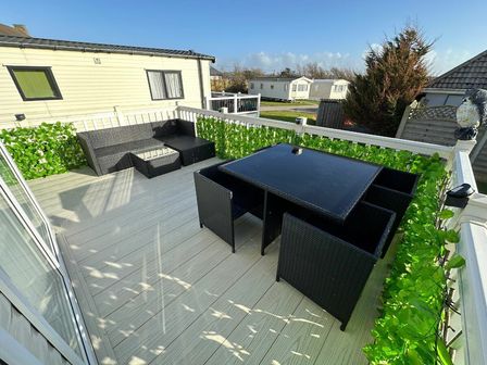 a terrace with a dining table and chairs surrounded by greenery at Bude Holiday Resort - Holiday Accommodation 16287, Bude