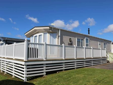 a mobile home with a deck surrounded by a white railing at Chesil Beach Holiday Park - Holiday Accommodation 16589 in Weymouth