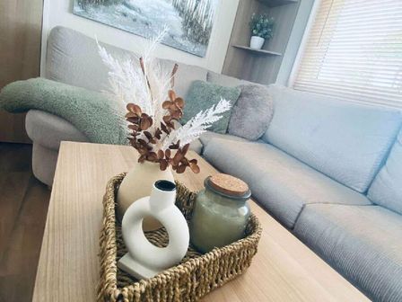 a decorative arrangement with flowers and a jar on a coffee table beside a couch at Presthaven Beach Resort - Holiday Accommodation 16736 in Prestatyn
