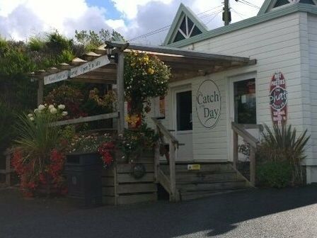 a building entrance with a wooden pergola and flower arrangements at Catch of the Day in Whitecross