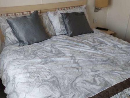 a bed with decorative pillows and a patterned bedspread at Pencnwc Holiday Park - Holiday Accommodation 16806 in New Quay