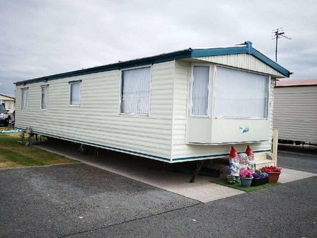 a caravan with windows and decorative gnomes outside at Happy Days Caravan Park - Holiday Accommodation 16827, Towyn