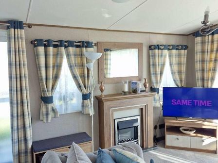 a living room with blue and yellow checkered curtains and a television at Lakeland Leisure Park - Holiday Accommodation 16942, Flookburgh