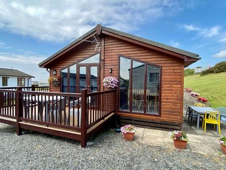 a wooden holiday lodge with a deck and planters at Port Haverigg Holiday Village - Holiday Accommodation 16965 in Millom