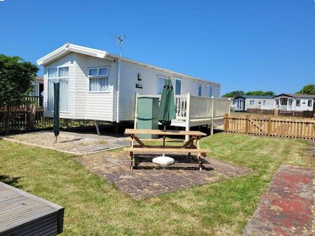 a holiday home with a deck and outdoor seating area at Unity Holiday Resort - Holiday Accommodation 17205, Burnham-on-Sea