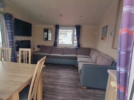 a living room with a large sectional sofa and a dining table at Caister Holiday Park - Holiday Accommodation 17332 in Great Yarmouth