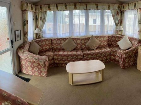 a living room with a large patterned sectional sofa and a wooden coffee table at Marsh Farm Holiday Park - Holiday Accommodation 17735 in Great Yarmouth