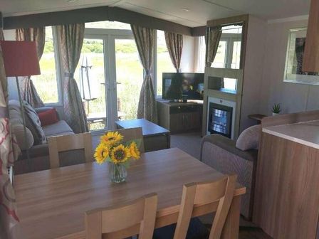 a living room with a television and a dining table at Lyons Sunnysands Holiday Park - Holiday Accommodation 17848 Talybont