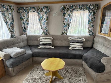 a seating area with a gray sectional sofa and a small wooden table at Aberystwyth Holiday Village - Holiday Accommodation 17908, Aberystwyth