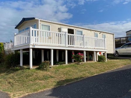 a holiday home on stilts with a deck and flowers at Swanage Bay View - Holiday Accommodation 17916 in Swanage