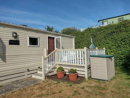 a mobile home with a deck, steps, and potted plants at Swanage Coastal Park - Holiday Accommodation 17991 in Swanage