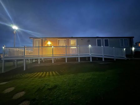 a holiday home illuminated at night with a ramp and porch at Devon Cliffs Holiday Park - Holiday Accommodation 18050 in Exmouth