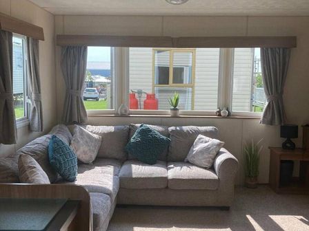 a living room with a gray sofa and decorative cushions at Cayton Bay Caravan Park - Holiday Accommodation 18183, Scarborough