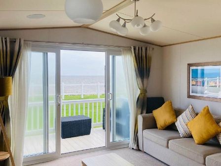 a living room with a sofa and a sliding door leading to a deck at Hopton Holiday Village - Holiday Accommodation 18341, Hopton