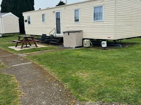 a trailer home with a picnic table and storage unit at Hafan y Mor Haven - Holiday Accommodation 18449 Pwllheli